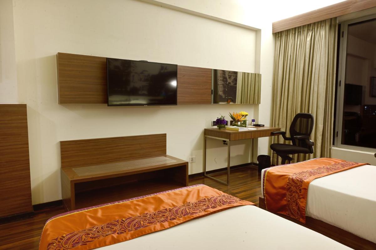 a hotel room with two beds and a desk at Vivanta Kolkata EM Bypass in Kolkata