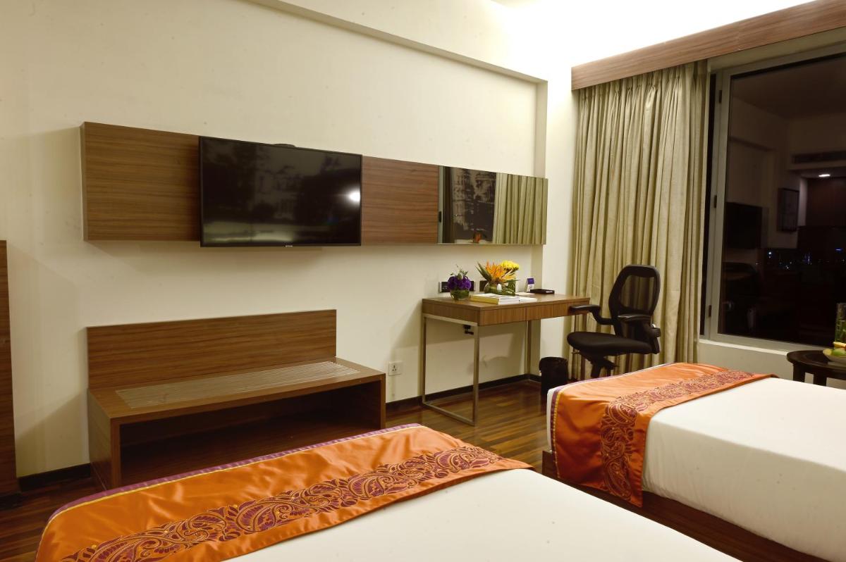 a hotel room with two beds and a desk at Vivanta Kolkata EM Bypass in Kolkata
