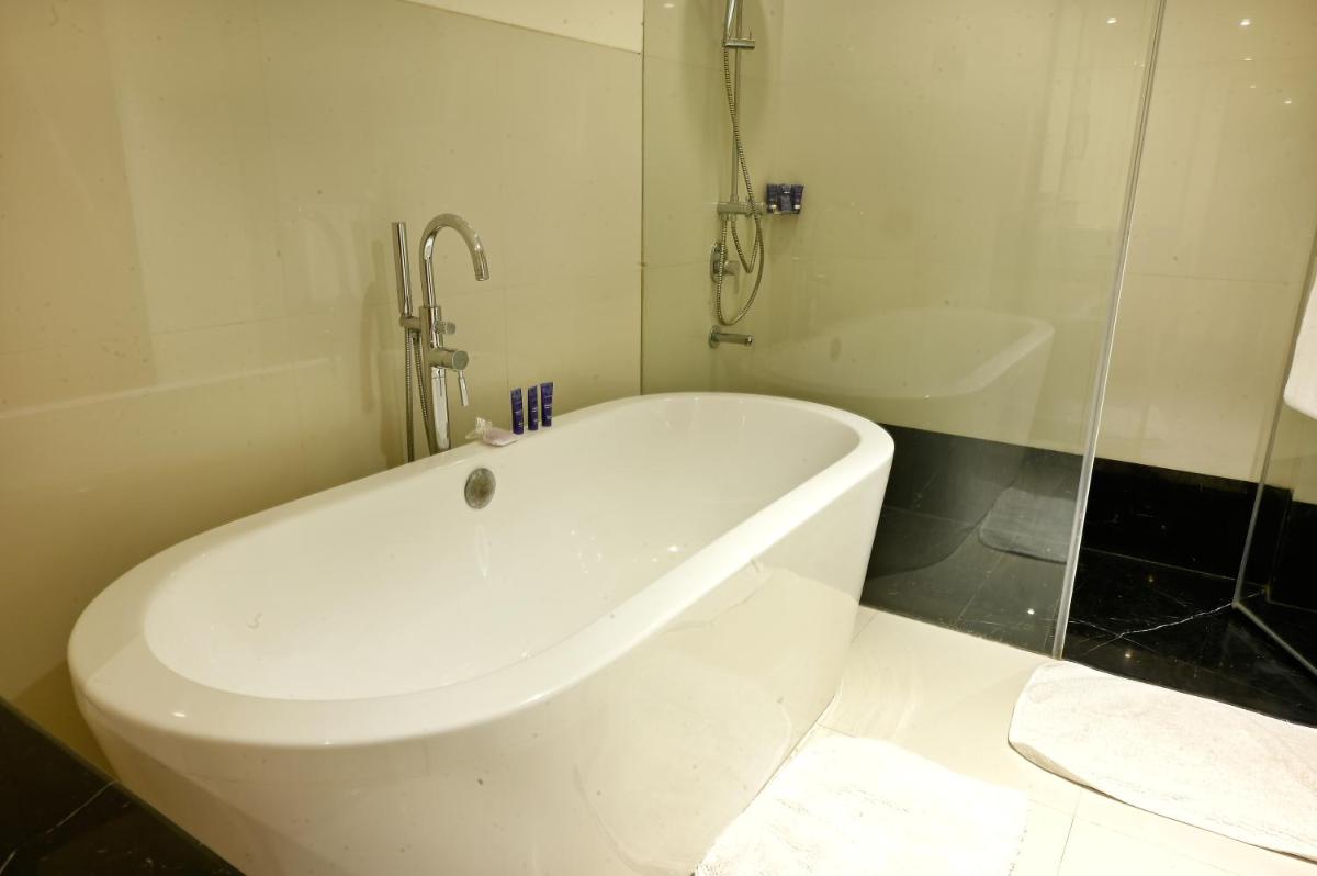 a white bath tub in a bathroom with a shower at Vivanta Kolkata EM Bypass in Kolkata