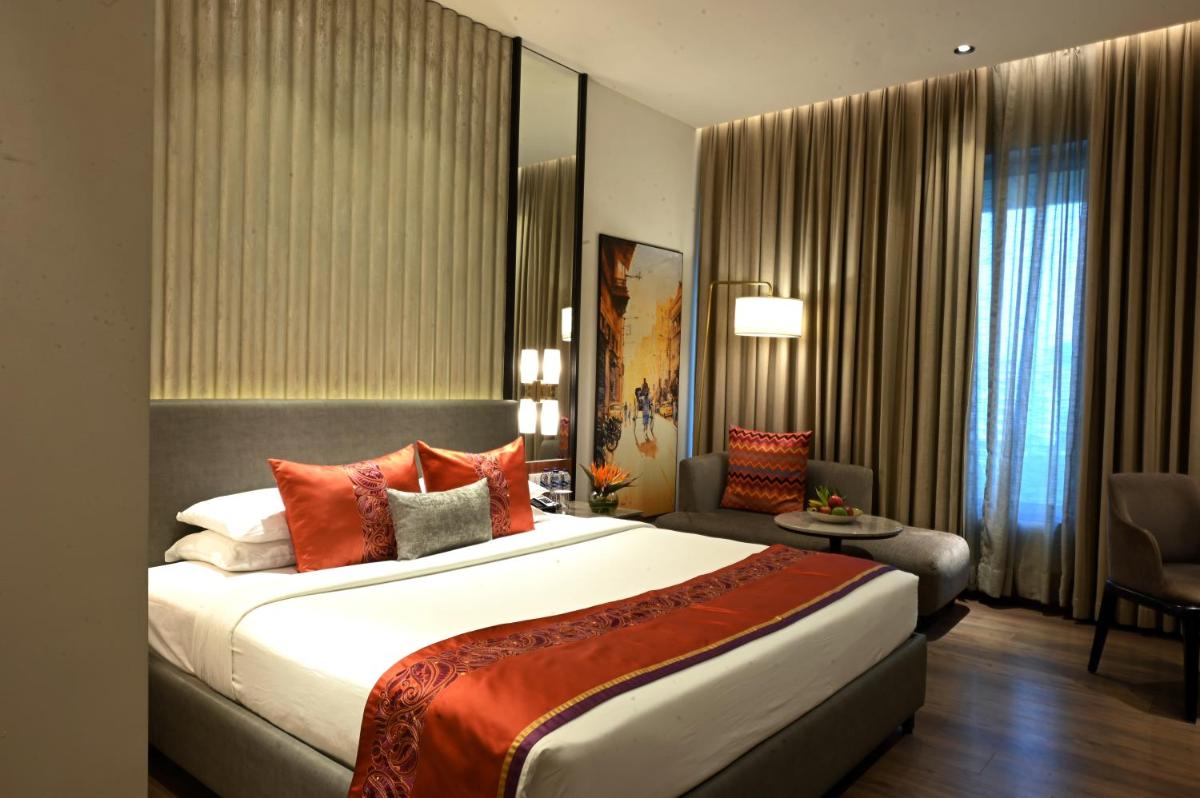 a hotel room with a large bed and a chair at Vivanta Kolkata EM Bypass in Kolkata