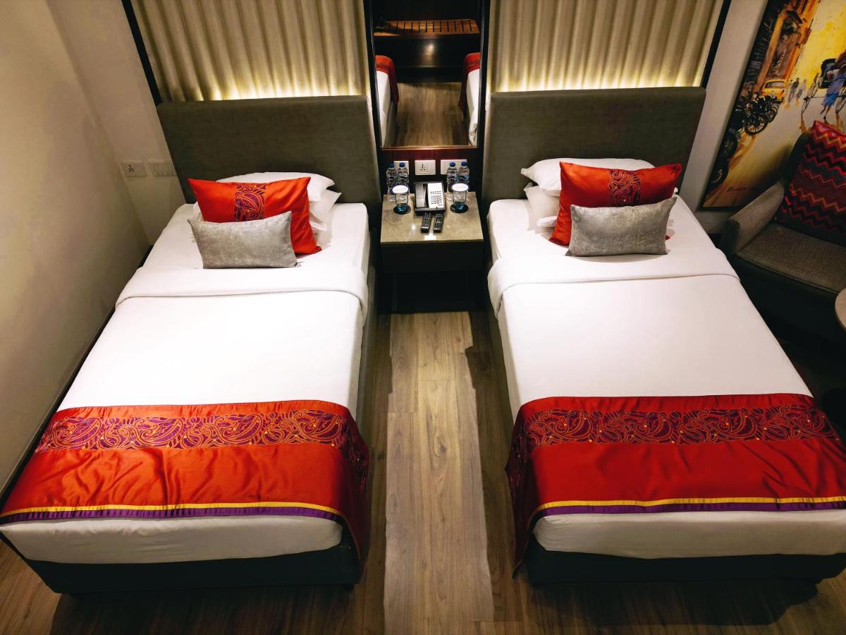 two beds with red pillows in a room at Vivanta Kolkata EM Bypass in Kolkata