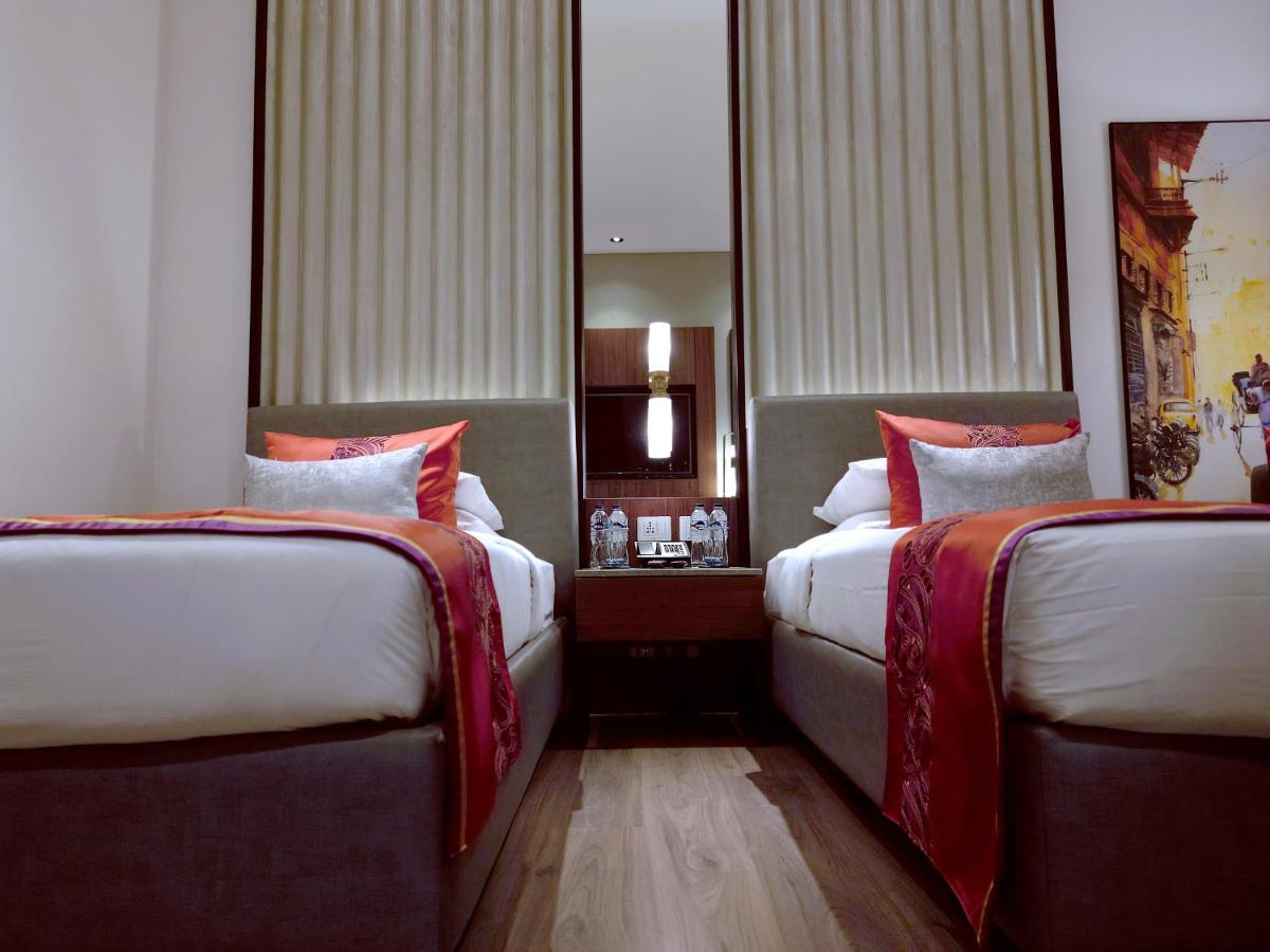a hotel room with two beds with red pillows at Vivanta Kolkata EM Bypass in Kolkata