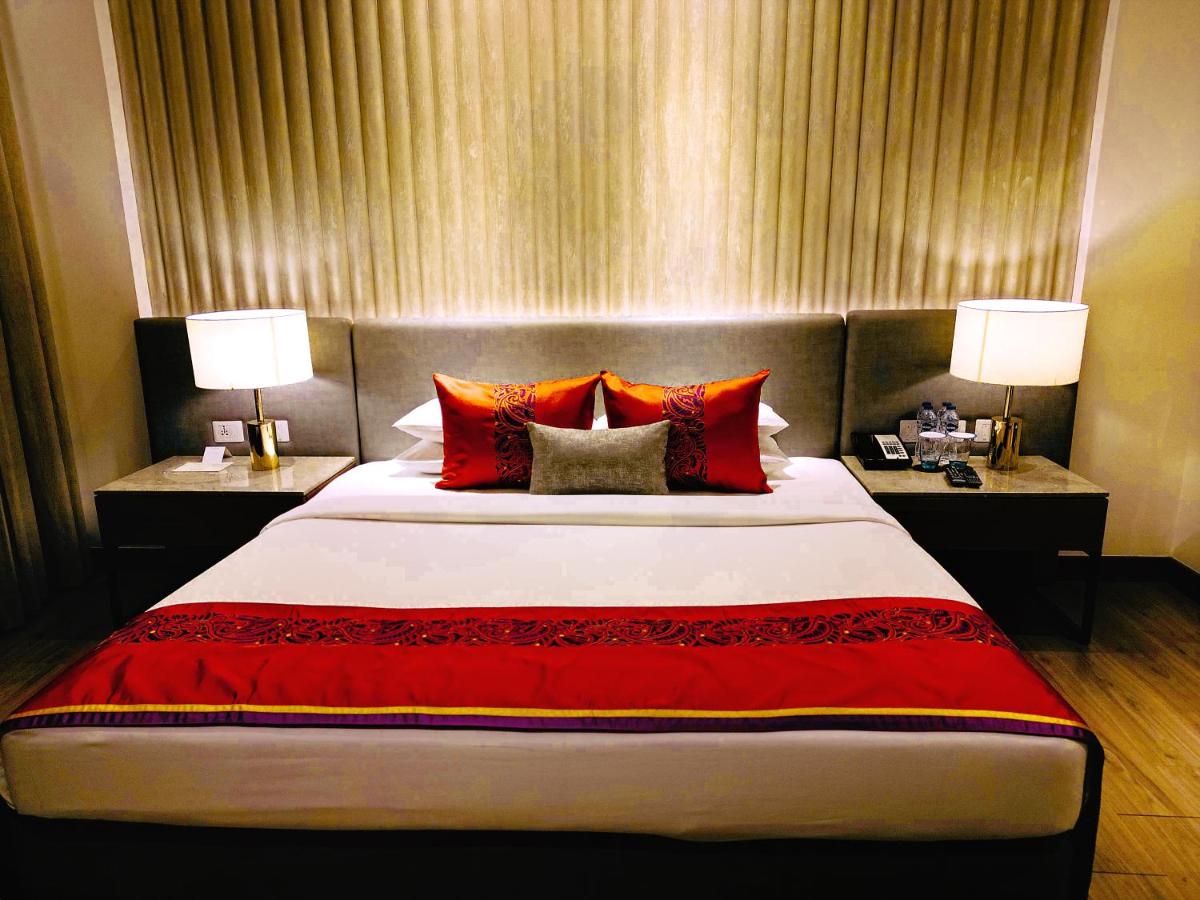 a bedroom with a large bed with red pillows at Vivanta Kolkata EM Bypass in Kolkata