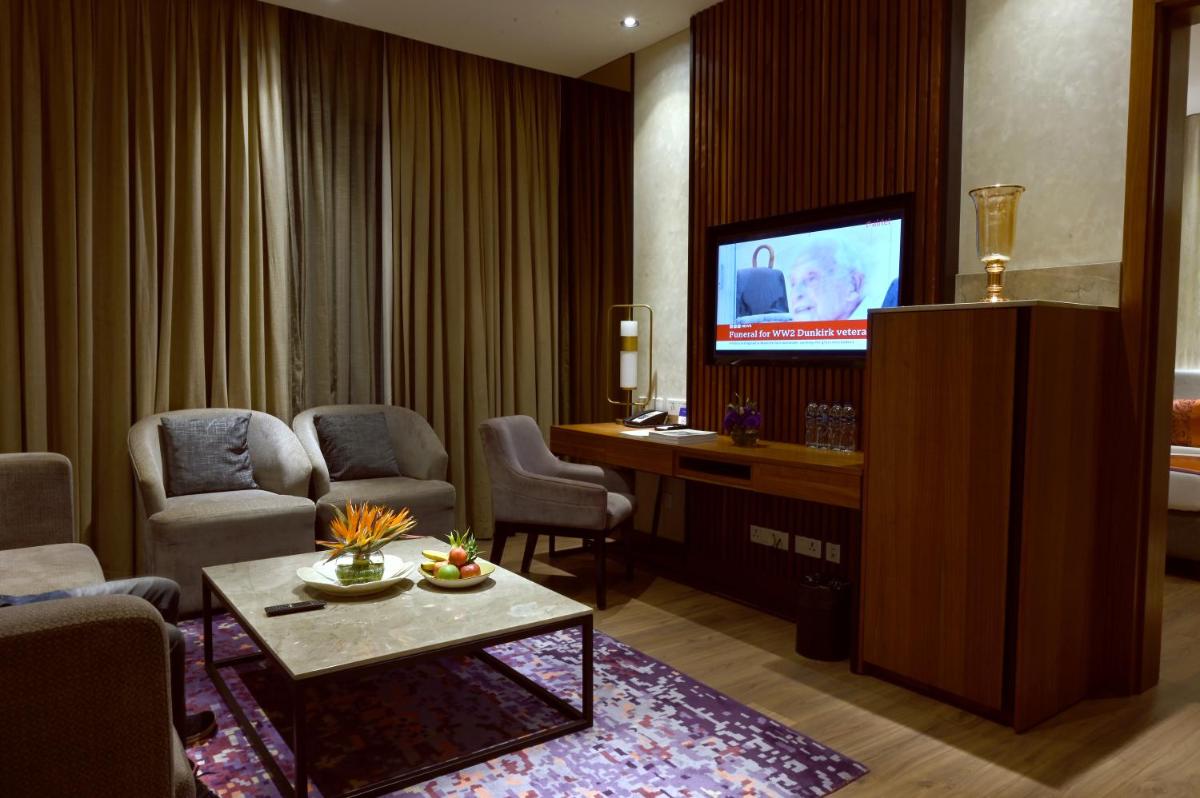 a living room with a tv and chairs and a table at Vivanta Kolkata EM Bypass in Kolkata