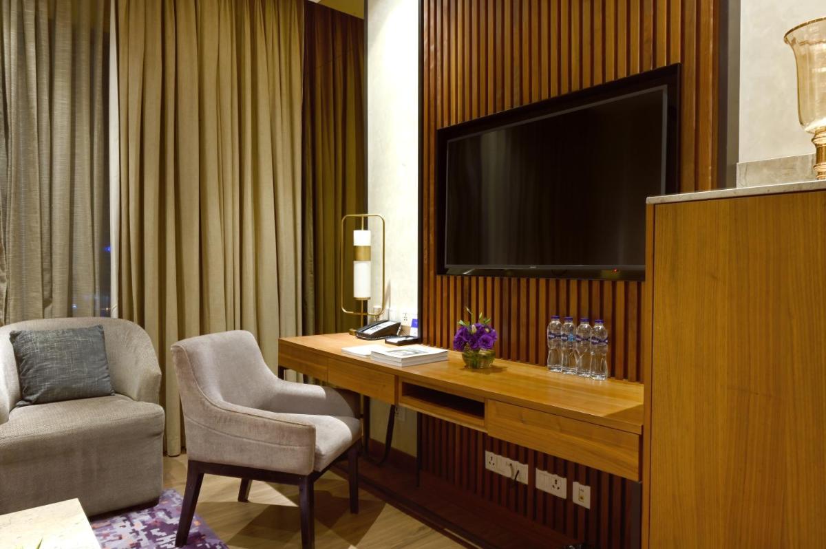 a hotel room with a desk with a tv and a chair at Vivanta Kolkata EM Bypass in Kolkata