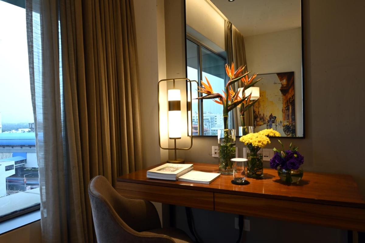 a hotel room with a desk with flowers and a mirror at Vivanta Kolkata EM Bypass in Kolkata