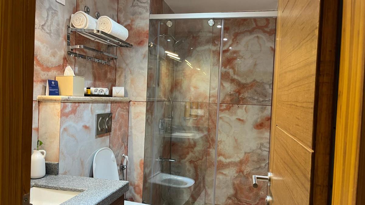 a bathroom with a shower with a toilet and a sink at The Prominence Mussoorie Road Dehradun in Dehradun