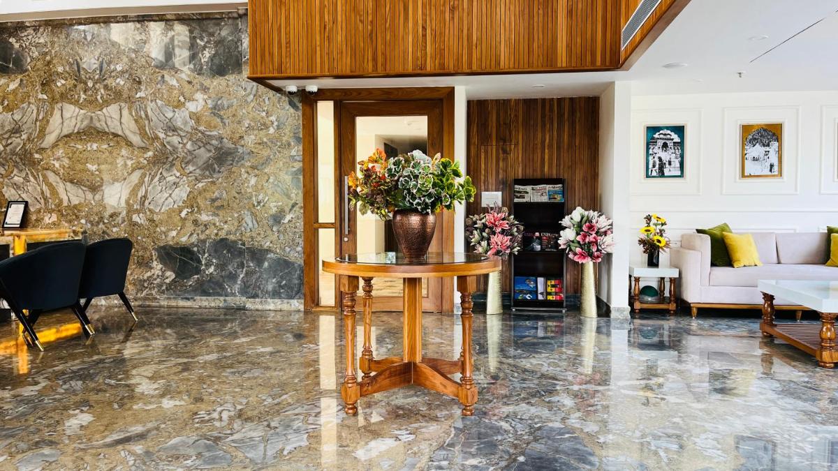 a living room with a table with a vase of flowers at The Prominence Mussoorie Road Dehradun in Dehradun