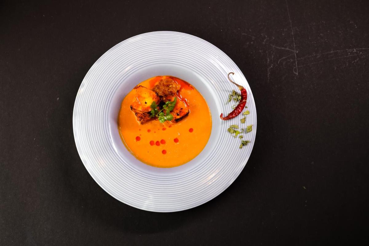 a white plate with a bowl of soup on a table at The Prominence Mussoorie Road Dehradun in Dehradun