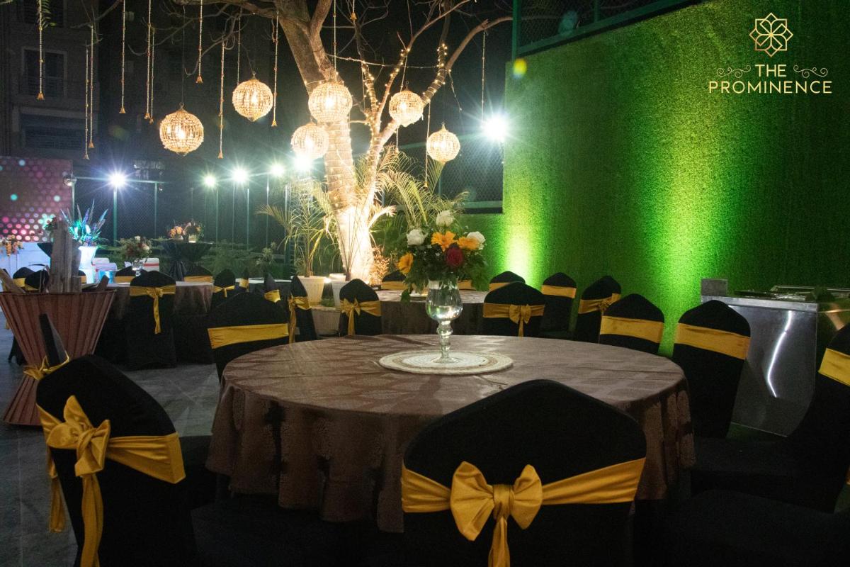 a table with chairs and a green wall with lights at The Prominence Mussoorie Road Dehradun in Dehradun