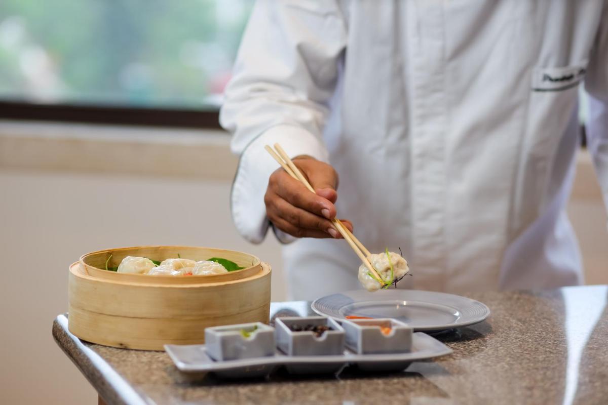 a chef is preparing food in a kitchen with chopsticks at The Prominence Mussoorie Road Dehradun in Dehradun