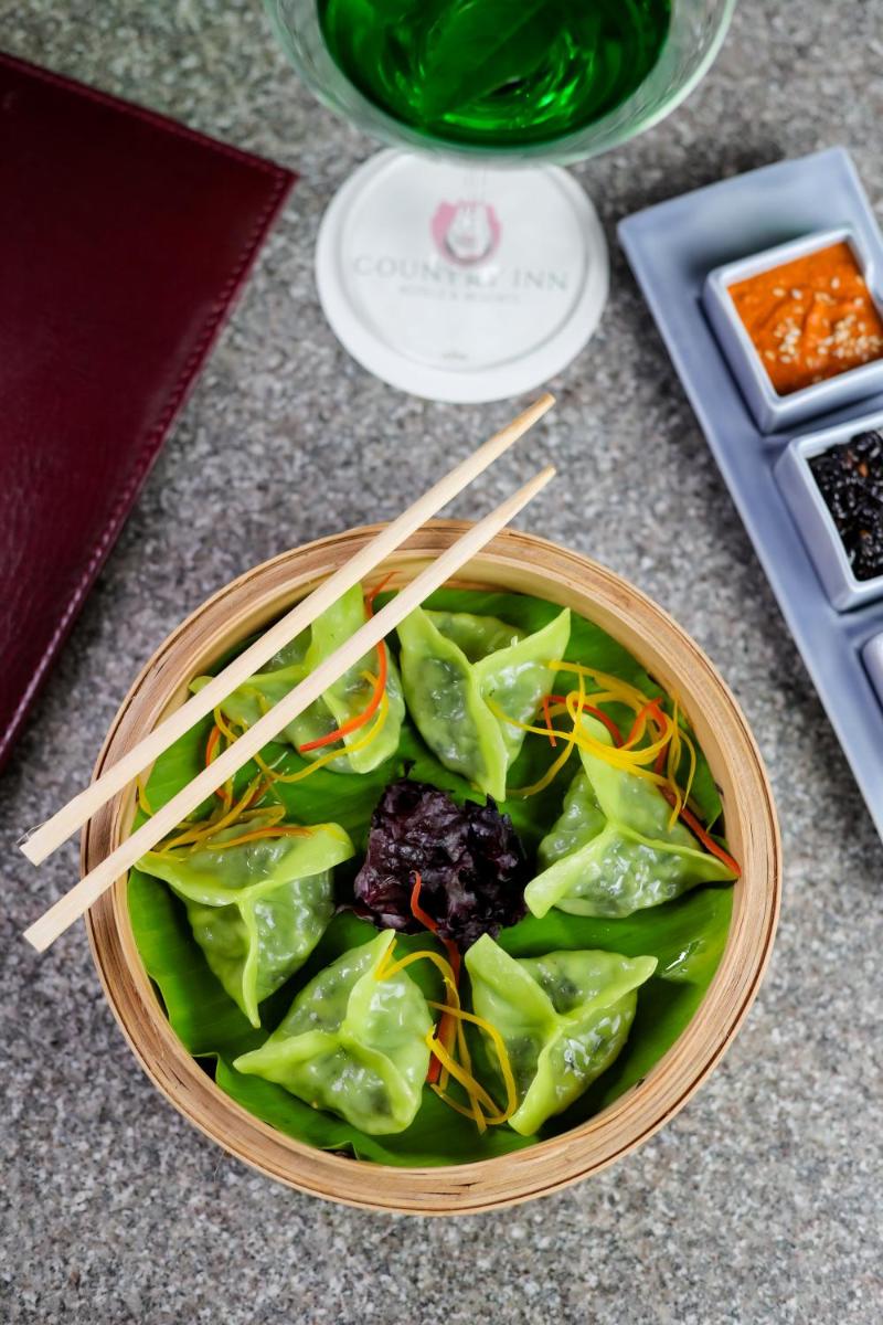 a bowl of greens with chopsticks on a table at The Prominence Mussoorie Road Dehradun in Dehradun