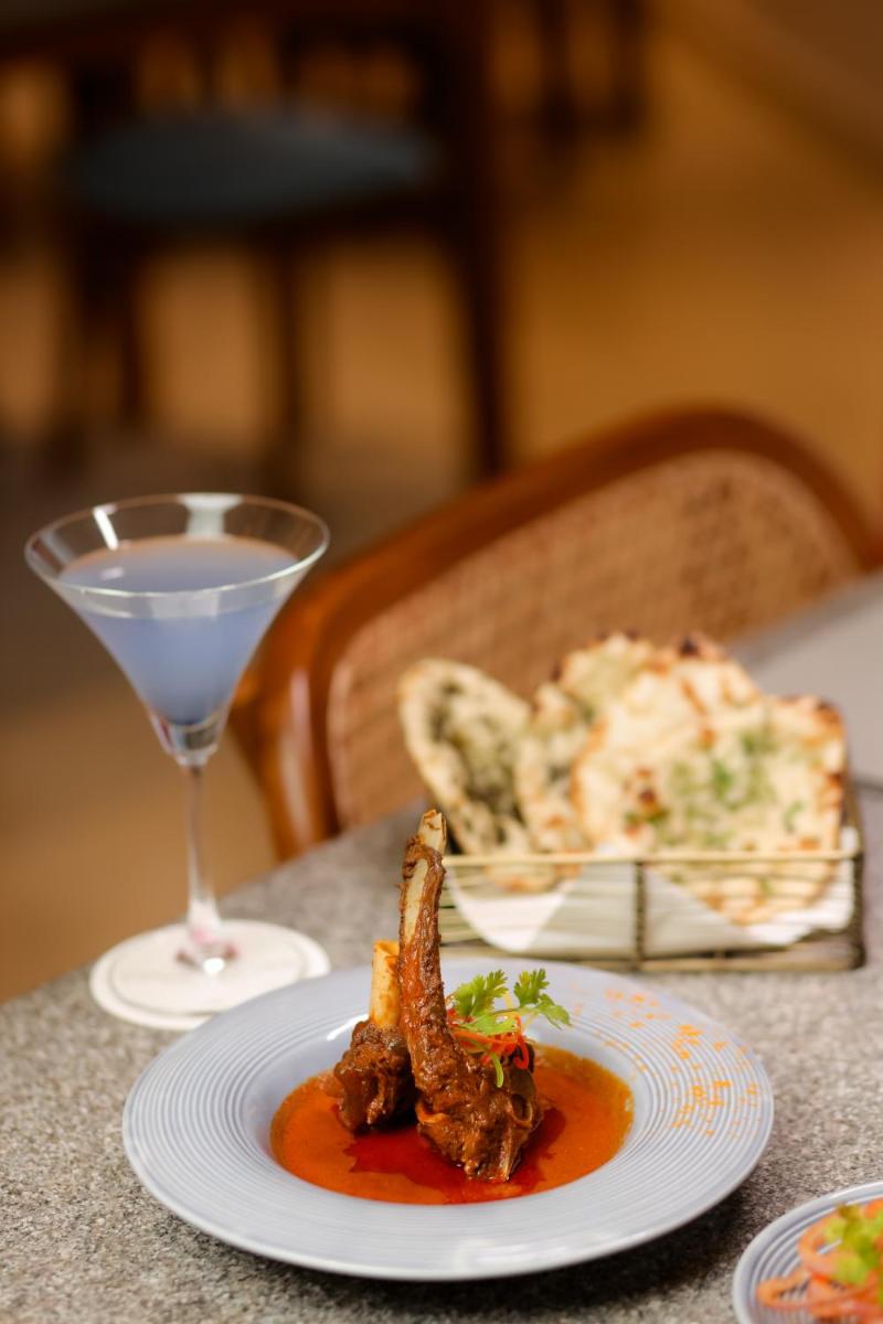 a table with a plate of food and a glass of wine at The Prominence Mussoorie Road Dehradun in Dehradun