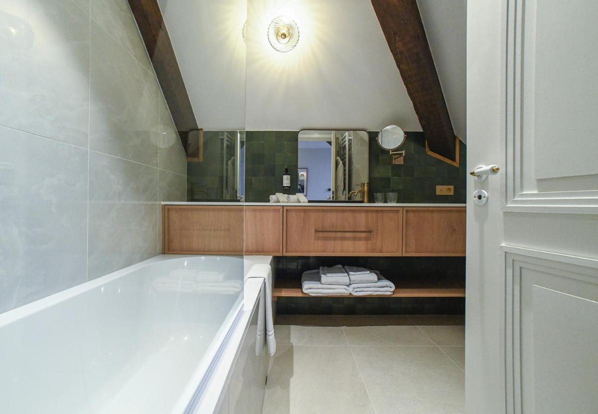 une salle de bain avec une baignoire et un grand miroir dans l'établissement Grand Hôtel Du Parc - Teritoria, à Aix-les-Bains