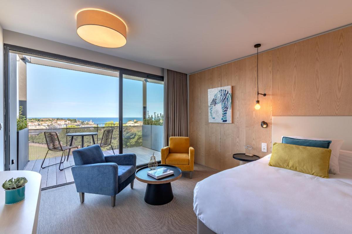 une chambre d'hôtel avec un lit et un salon dans l'établissement Les Jardins du Cèdre, Boutique hôtel & gastronomie, à Port-Vendres