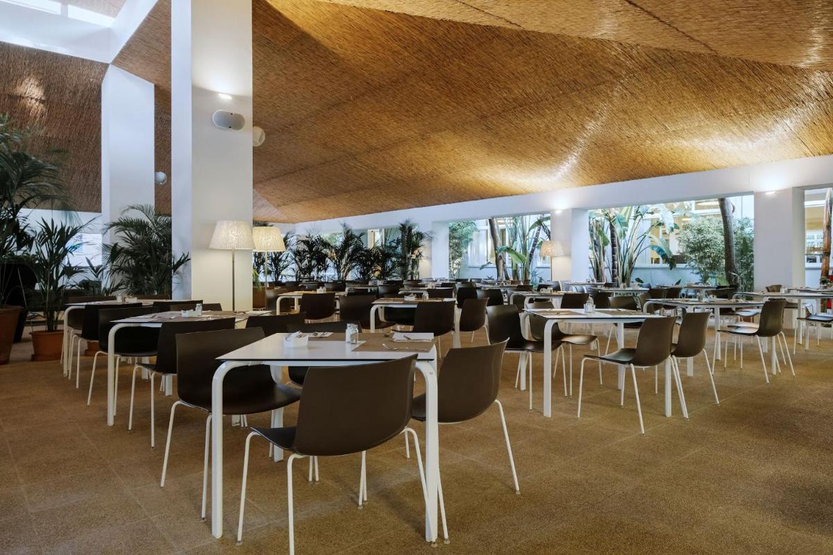 Un restaurante con mesas y sillas en una habitación. en Prinsotel La Pineda, en Cala Ratjada