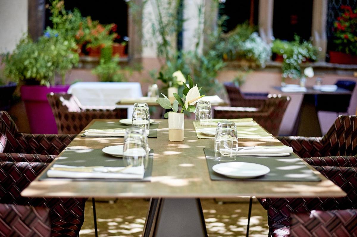 une table en bois avec des assiettes et des verres dans l'établissement Relais & Châteaux La Maison Des Têtes, à Colmar