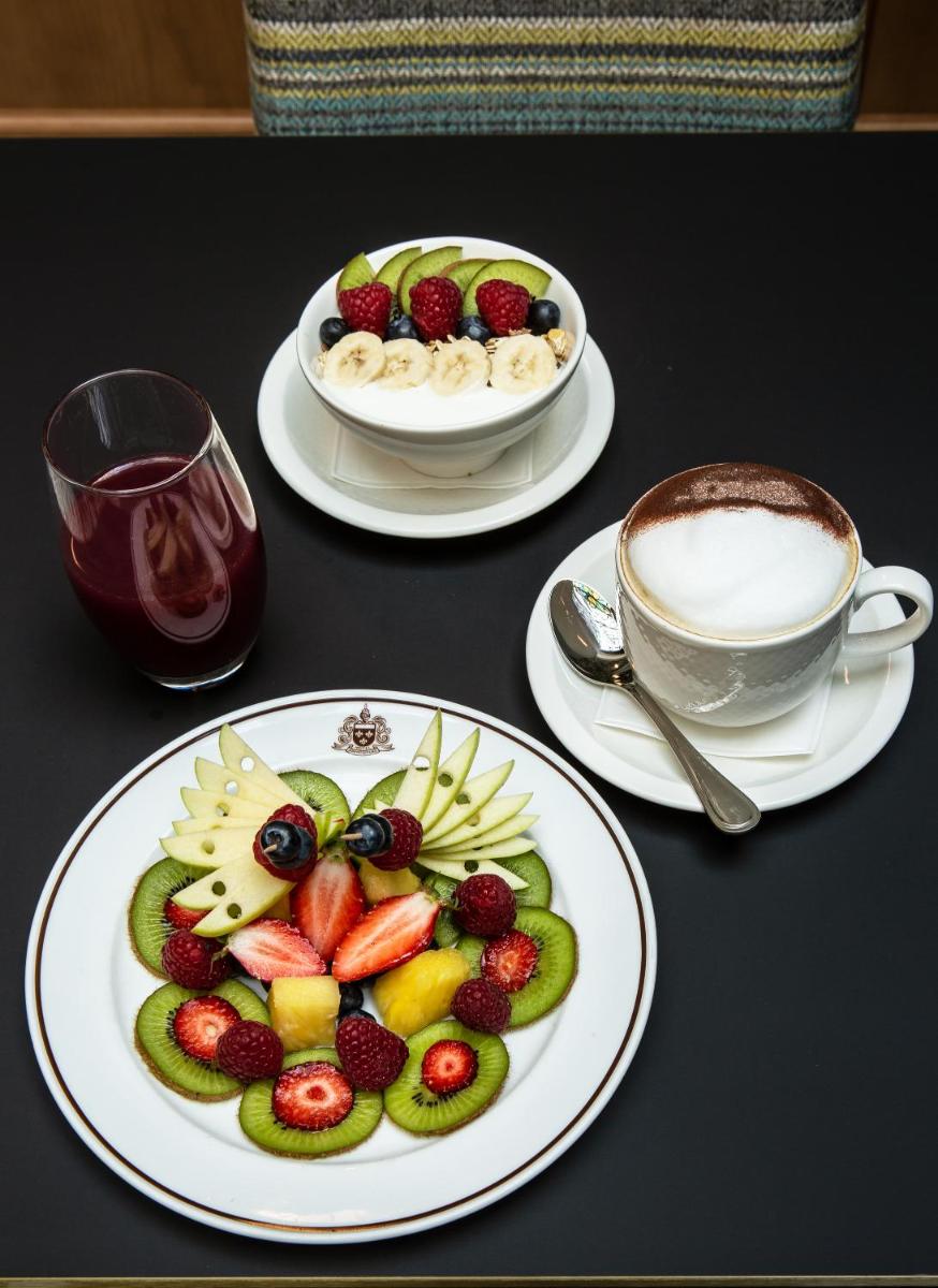 - une table avec deux assiettes de fruits et une tasse de café dans l'établissement Hôtel Saint-Pétersbourg Opéra & Spa, à Paris