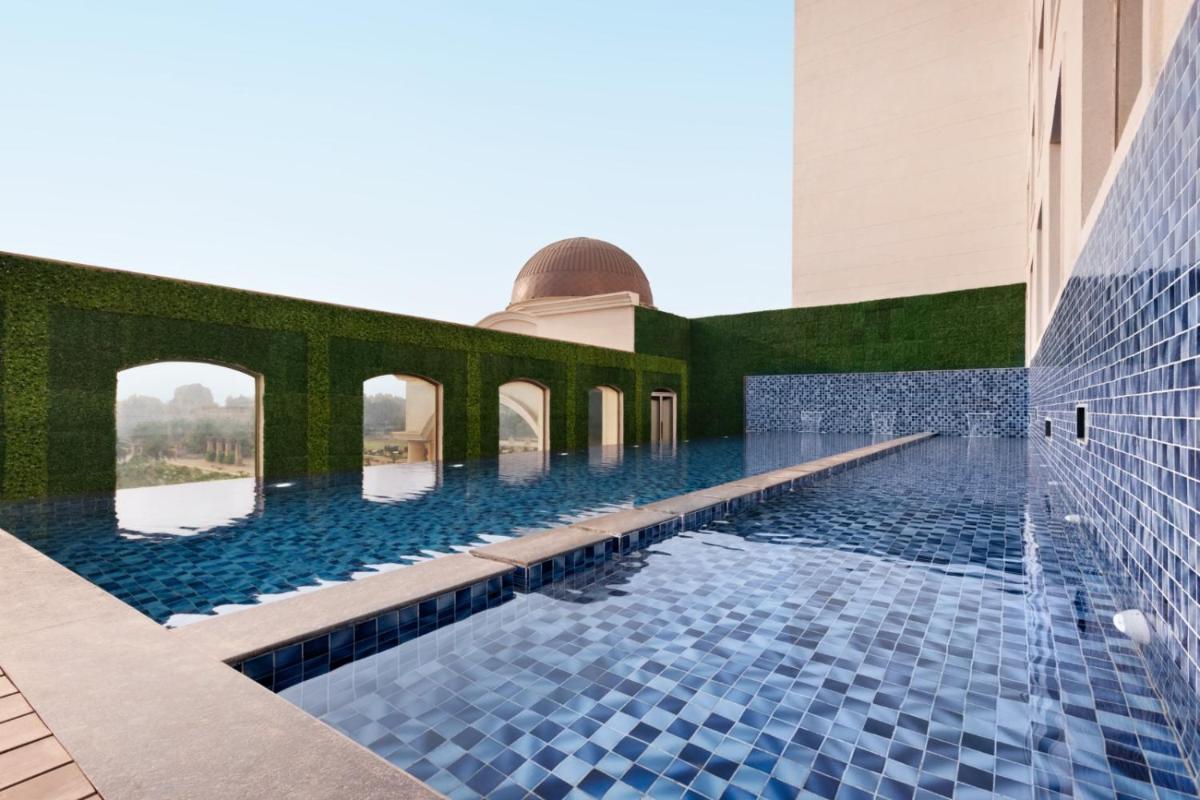 a swimming pool in a building with blue tiles at Ramada by Wyndham Lucknow Hotel and Convention Center in Lucknow