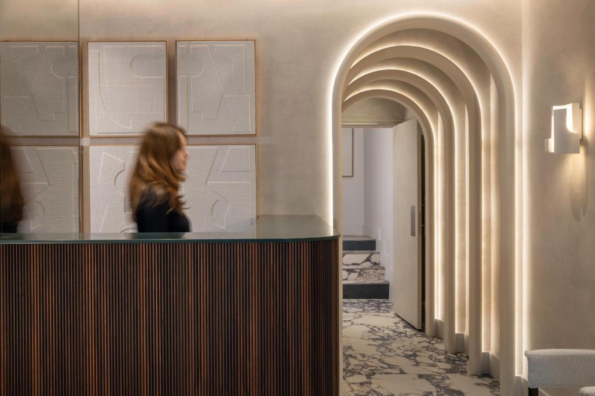 une femme est assise à un comptoir dans un bâtiment dans l'établissement Hotel des Carmes by Malone, à Paris