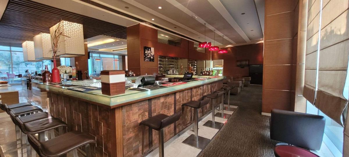 a restaurant with a bar with leather chairs at Radisson Blu Hotel, Greater Noida in Greater Noida