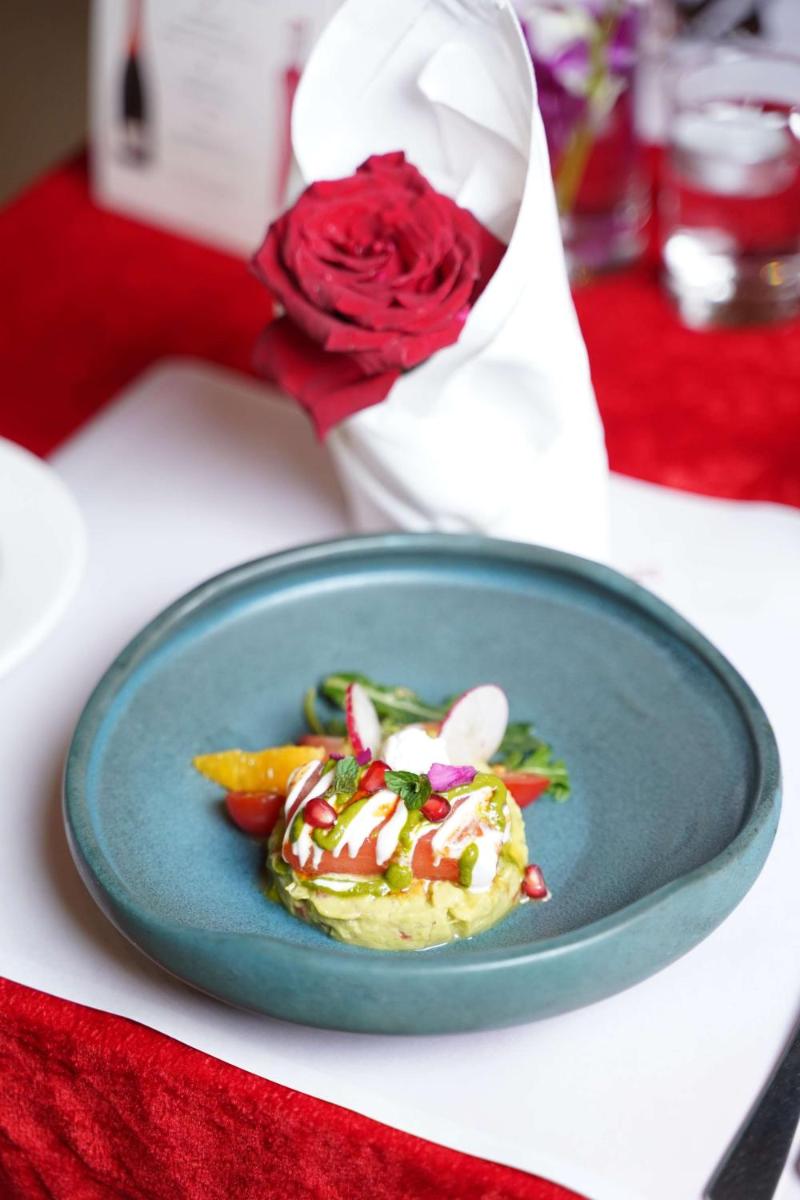 a blue plate with food on a table with a rose at Radisson Blu Hotel, Greater Noida in Greater Noida
