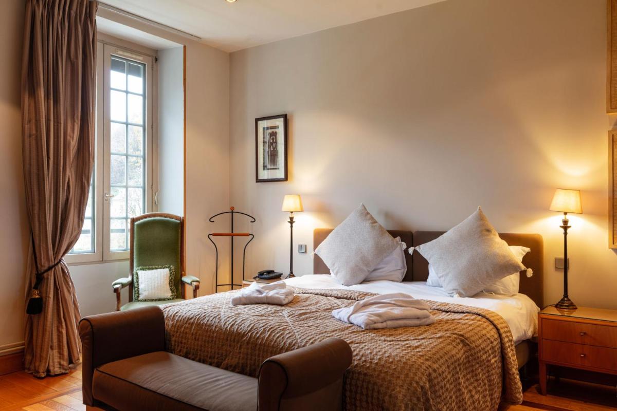 une chambre d'hôtel avec un lit et une chaise dans l'établissement Grand Hôtel & Spa Uriage, à Uriage-les-Bains