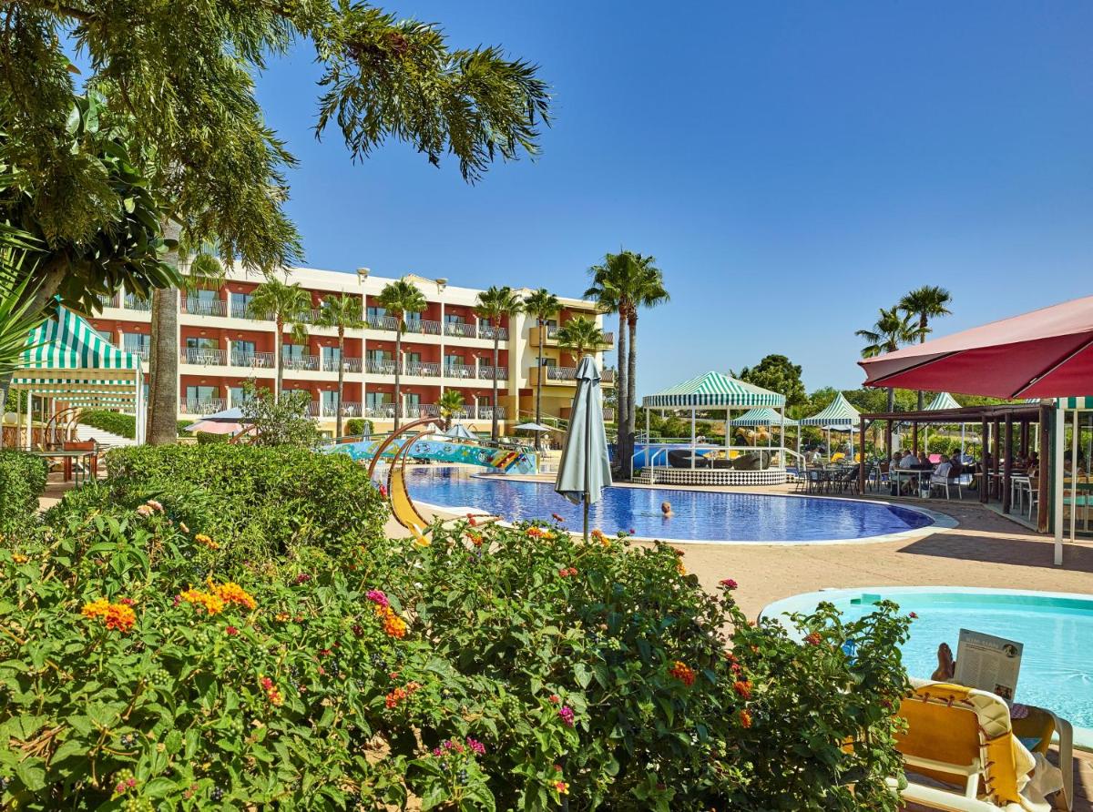 uma piscina de resort com um hotel ao fundo em Hotel Baia Grande em Albufeira