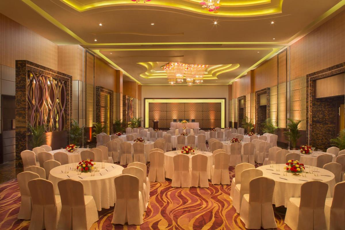 a banquet hall with white tables and white chairs at Radisson Blu Hotel, Indore in Indore
