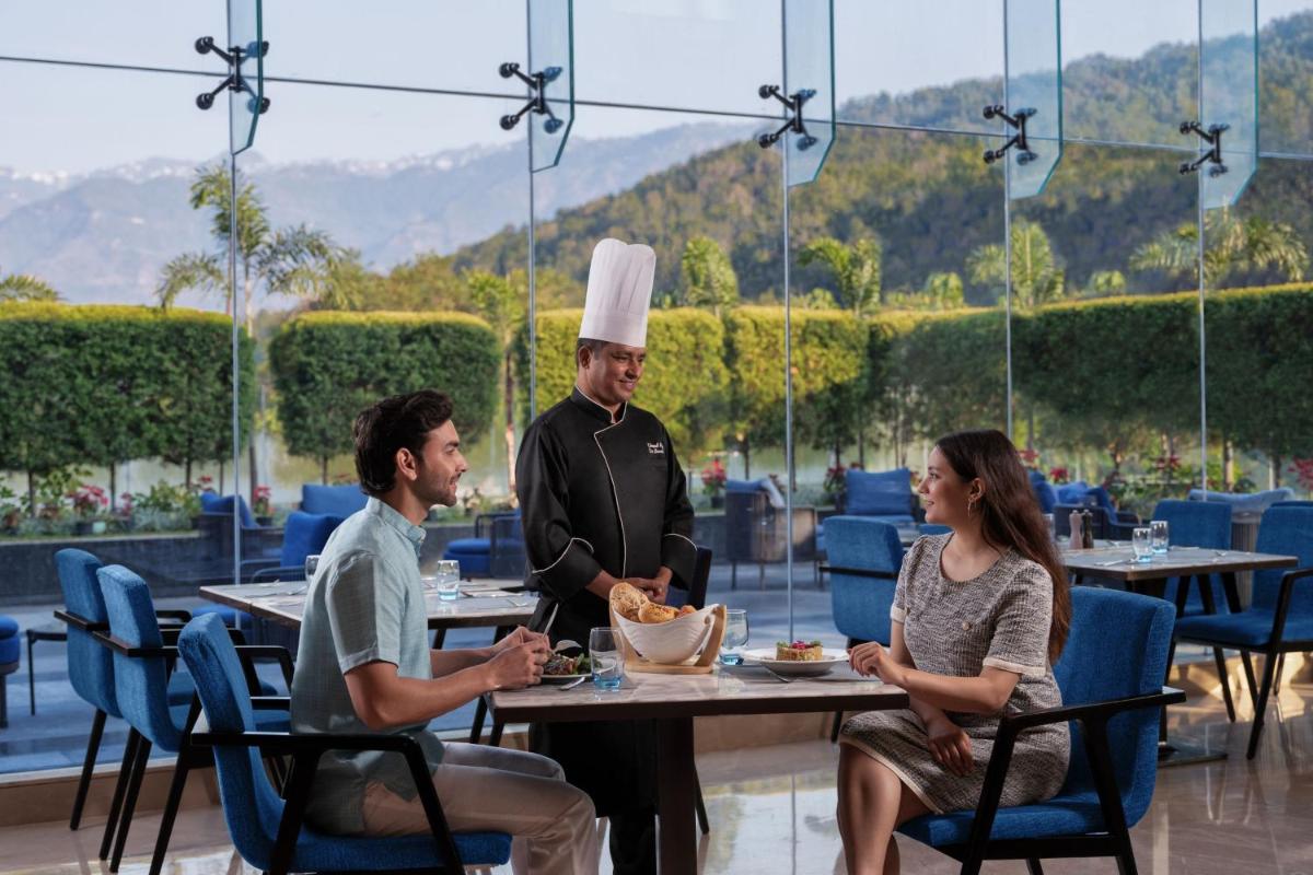 a man in a chefs hat standing at a table in a restaurant at Fairfield by Marriott Dehradun in Dehradun