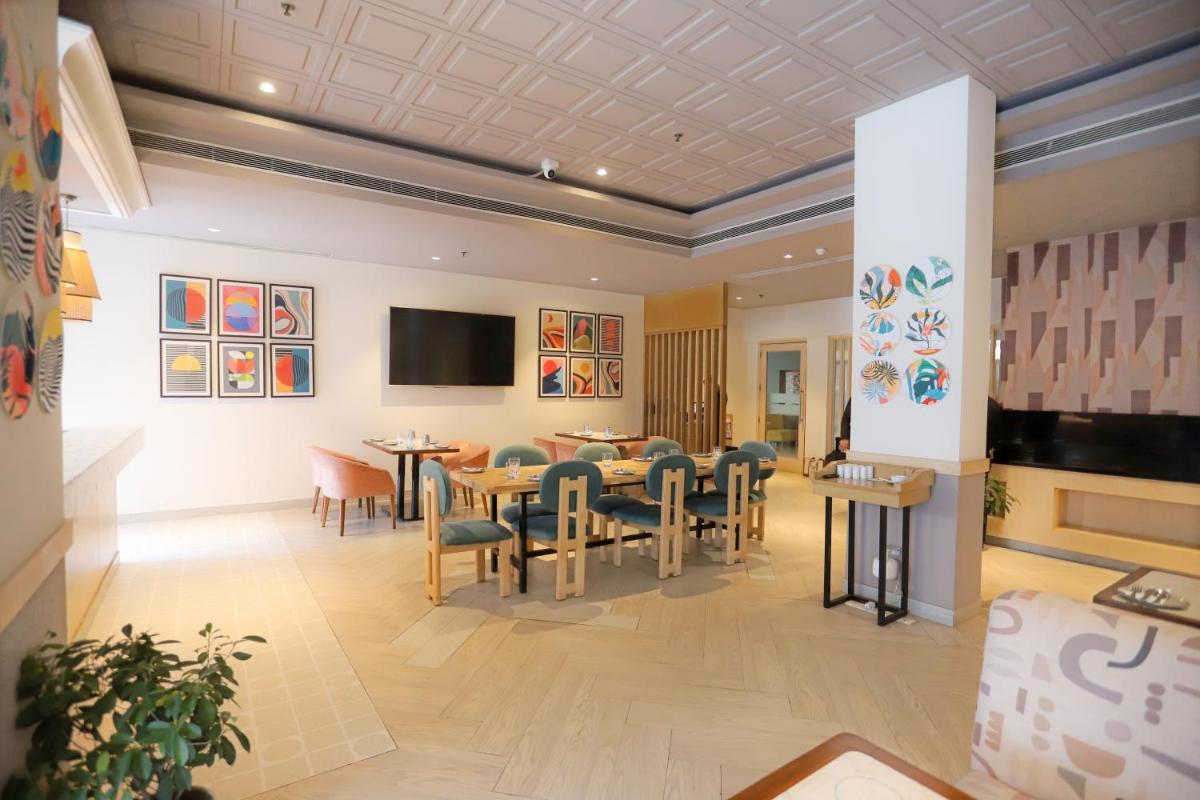 a dining room with tables and chairs and a tv at Park Inn by Radisson,South Delhi in New Delhi a dining room with tables and chairs and a tv at Park Inn by Radisson,South Delhi in New Delhi