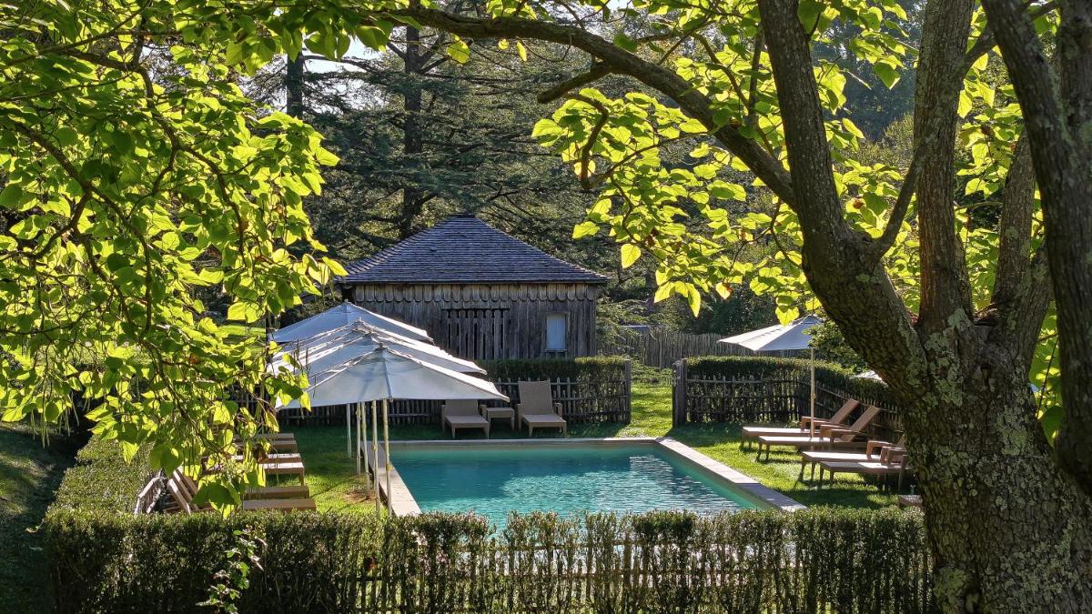 une piscine avec un parasol et des chaises et un gazebo dans l'établissement La Bastide en Gascogne, à Barbotan-les-Thermes