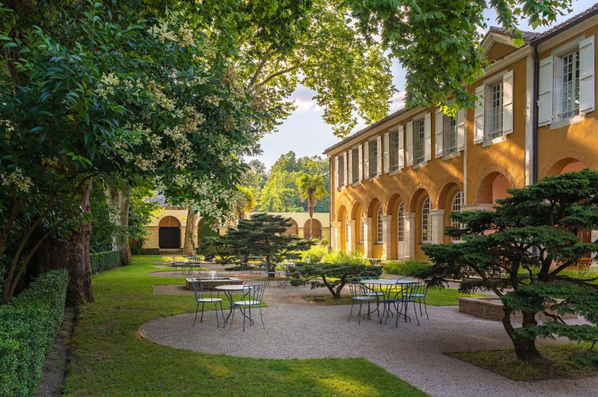 une cour avec des tables et des chaises et un bâtiment dans l'établissement La Bastide en Gascogne, à Barbotan-les-Thermes