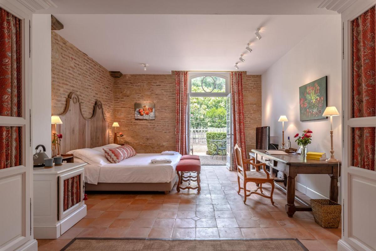 une chambre avec un lit et un bureau dans une pièce dans l'établissement La Bastide en Gascogne, à Barbotan-les-Thermes