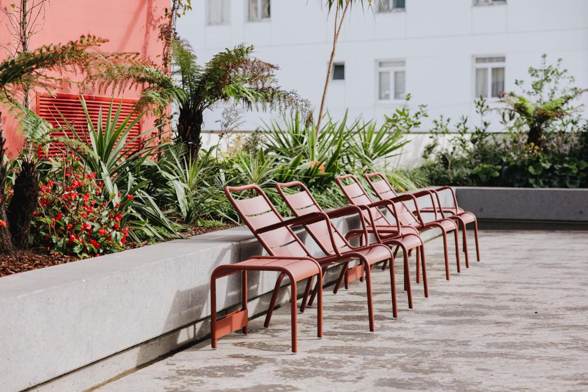uma fila de cadeiras sentadas ao lado de uma parede em NINE DOTS Azorean Art Boutique Hotel em Ponta Delgada