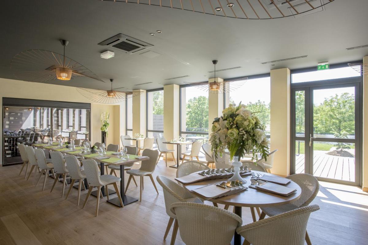 une salle à manger avec tables, chaises et fenêtres dans l'établissement Hotel de L'Abbaye Le Tronchet - Handwritten Collection, au Tronchet