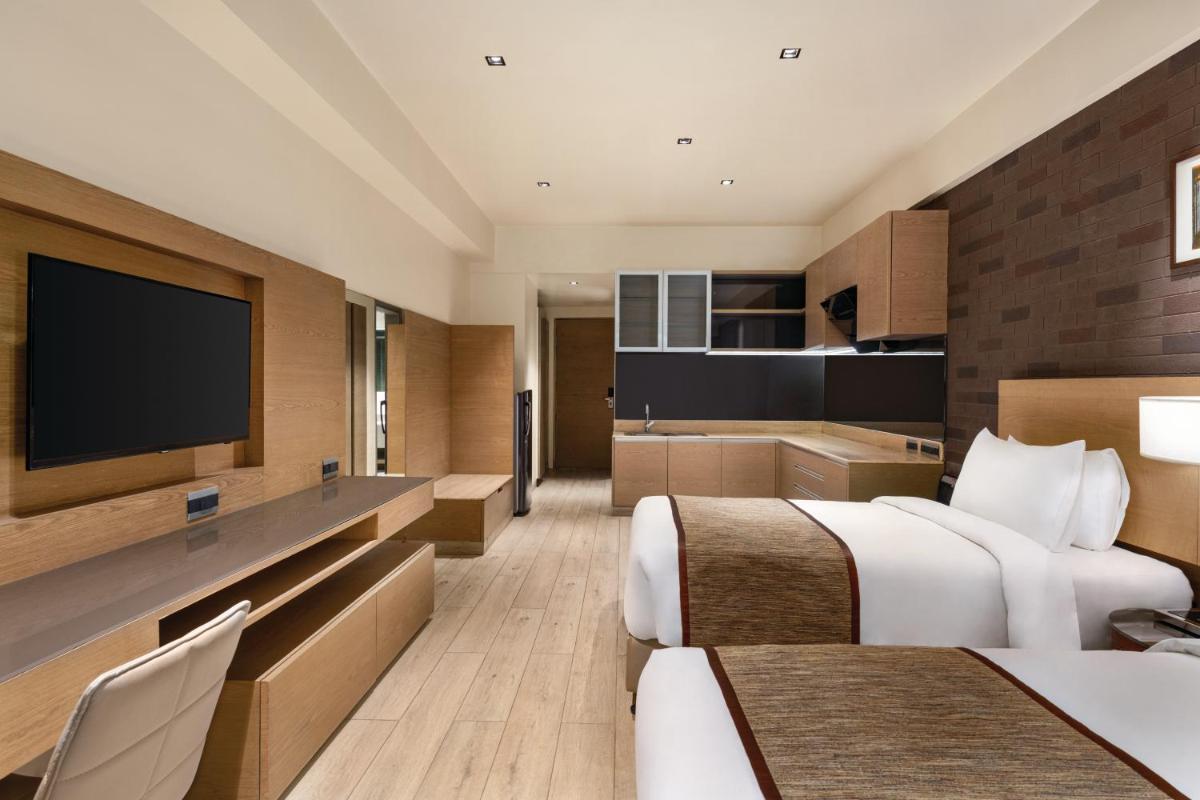 a hotel room with two beds and a flat screen tv at Wyndham Ahmedabad Shela in Ahmedabad
