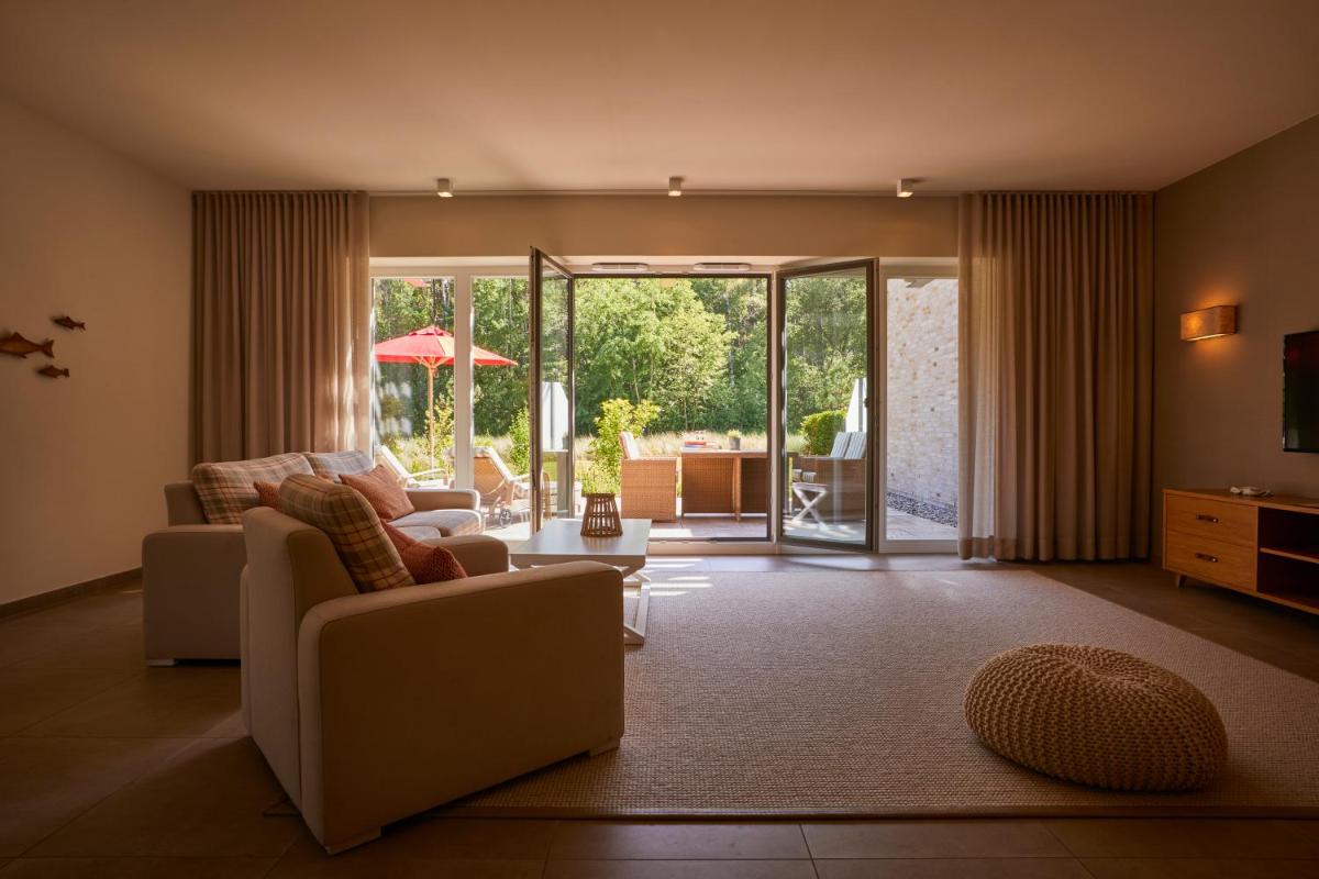 ein Wohnzimmer mit einer Couch und einem Sessel in der Unterkunft Aalernhüs hotel & spa in Sankt Peter-Ording