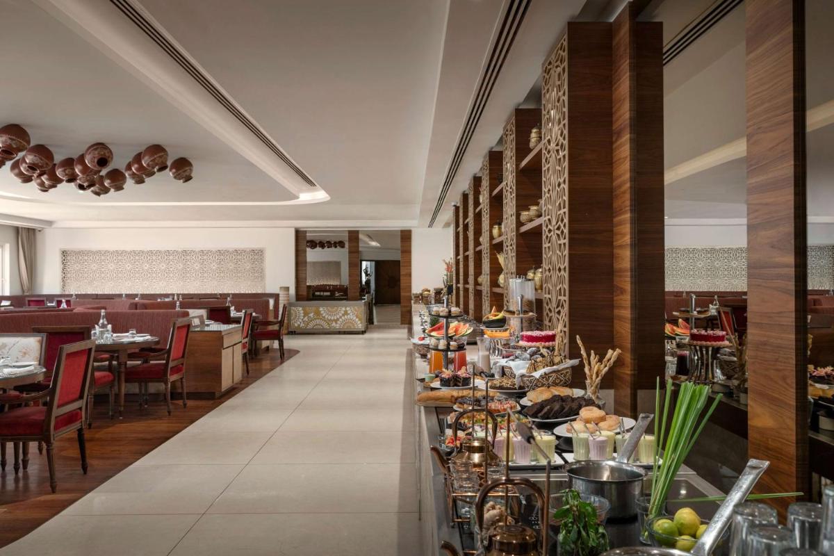 a restaurant with a buffet of food on a counter at Hawthorn Suites by Wyndham Dwarka in Dwarka a restaurant with a buffet of food on a counter at Hawthorn Suites by Wyndham Dwarka in Dwarka