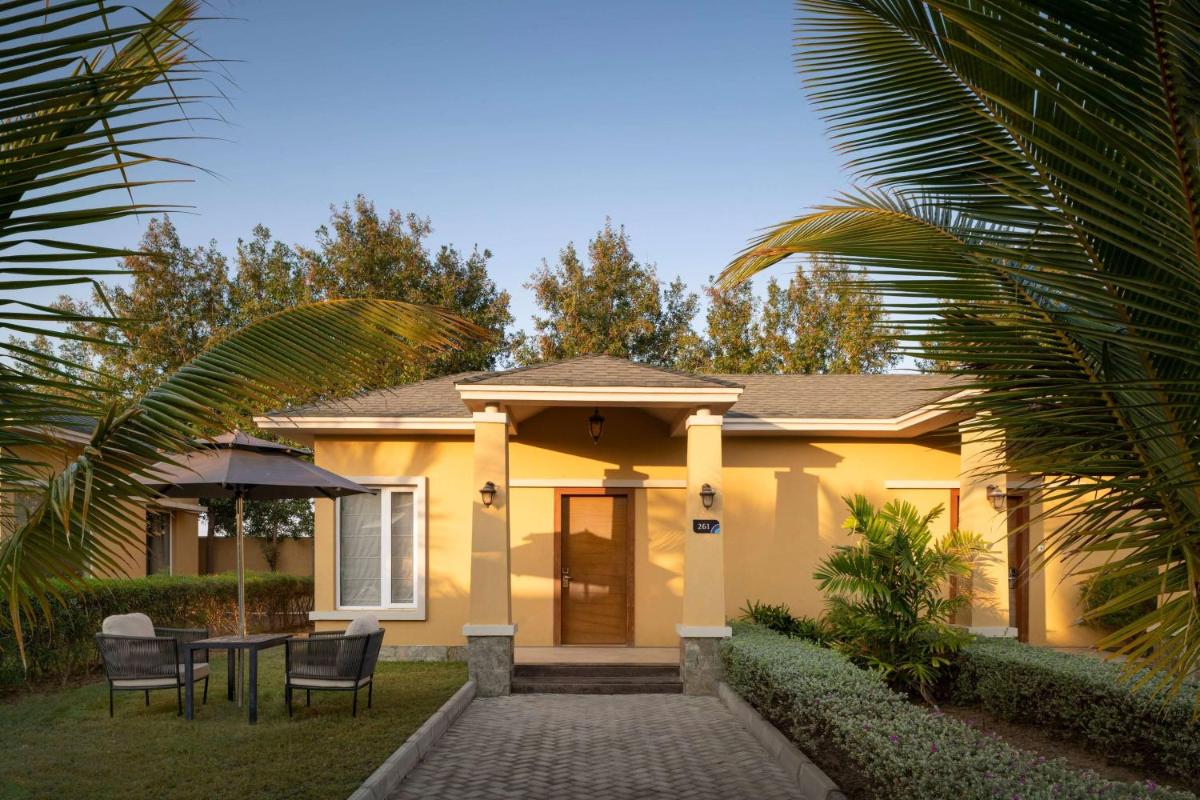 a yellow house with a table and chairs in front of it at Hawthorn Suites by Wyndham Dwarka in Dwarka a yellow house with a table and chairs in front of it at Hawthorn Suites by Wyndham Dwarka in Dwarka