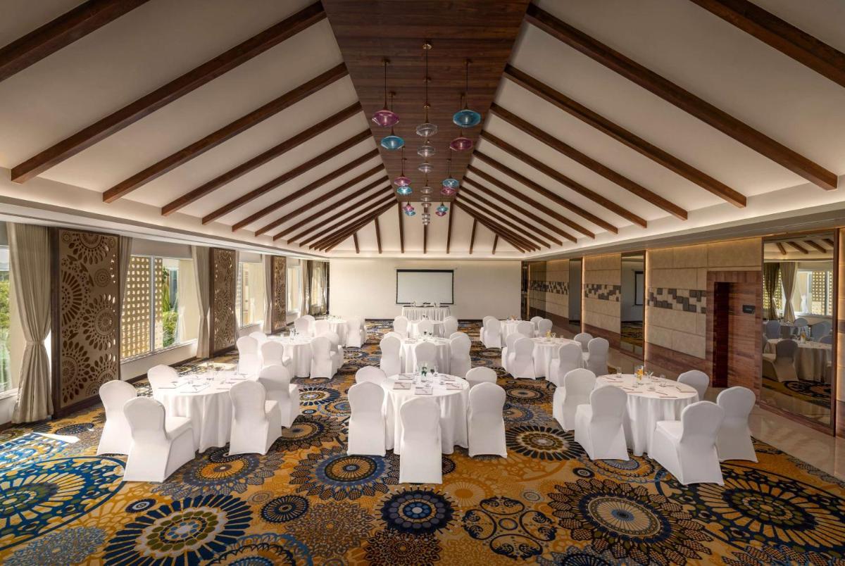 a banquet hall with white tables and white chairs at Hawthorn Suites by Wyndham Dwarka in Dwarka a banquet hall with white tables and white chairs at Hawthorn Suites by Wyndham Dwarka in Dwarka