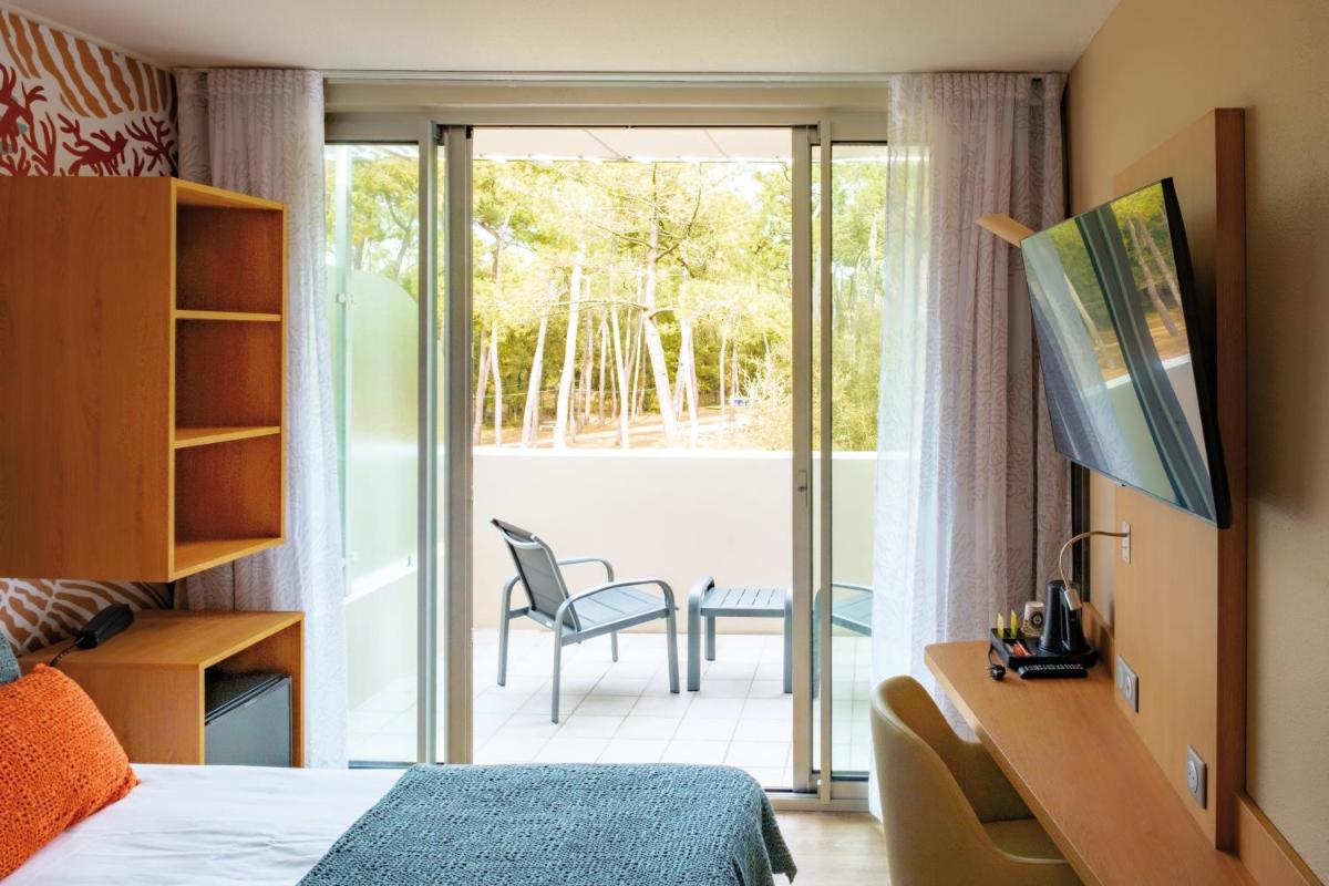 une chambre avec un lit et une porte coulissante en verre dans l'établissement Club Vacances Bleues Les Jardins De l'Atlantique, à Talmont-Saint-Hilaire