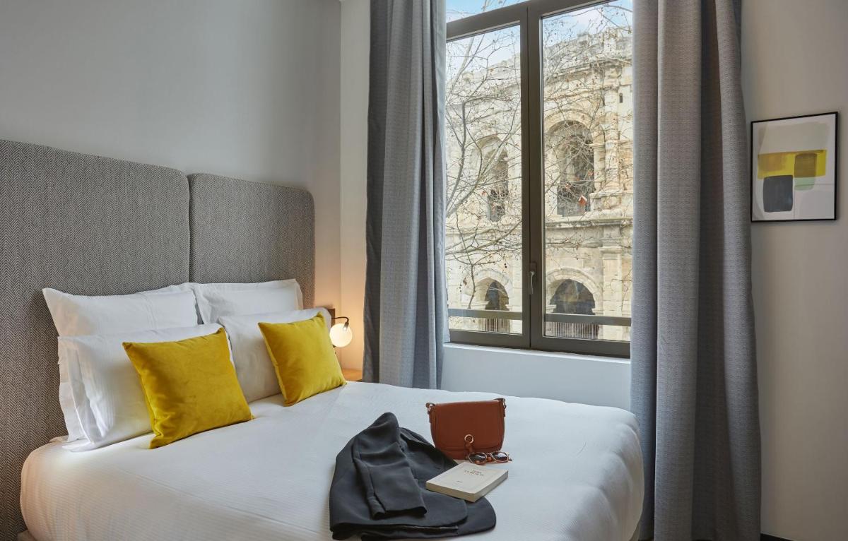 une chambre d'hôtel avec un lit, un ordinateur portable et une fenêtre dans l'établissement Appart'hôtel Odalys City - Nîmes Arènes - Palais des Congrès, à Nîmes