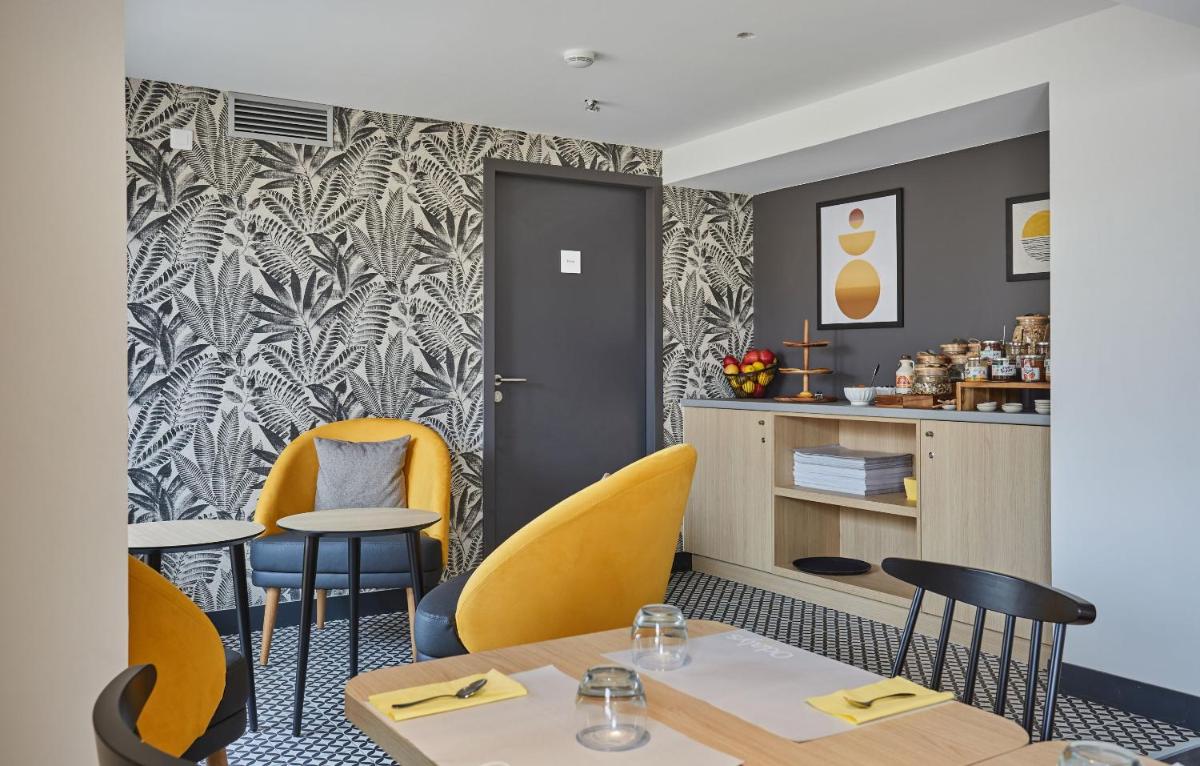 un restaurant avec des chaises et des tables jaunes et un mur dans l'établissement Appart'hôtel Odalys City - Nîmes Arènes - Palais des Congrès, à Nîmes