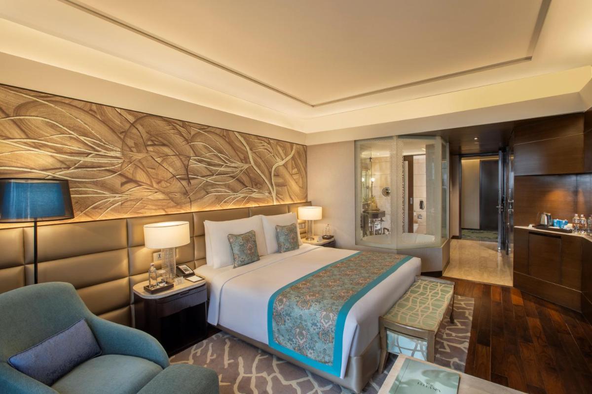 a hotel room with a bed and a chair at The Leela Ambience Convention Hotel Delhi in New Delhi