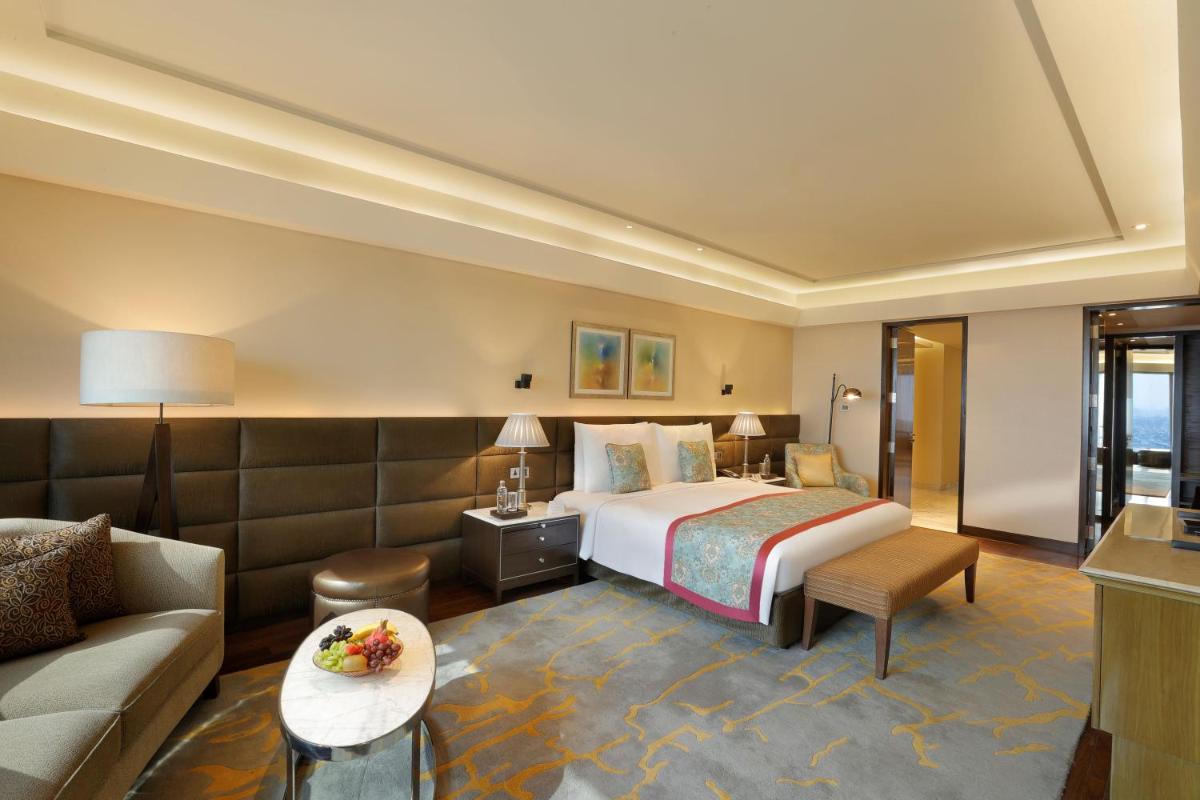 a hotel room with a bed and a couch at The Leela Ambience Convention Hotel Delhi in New Delhi