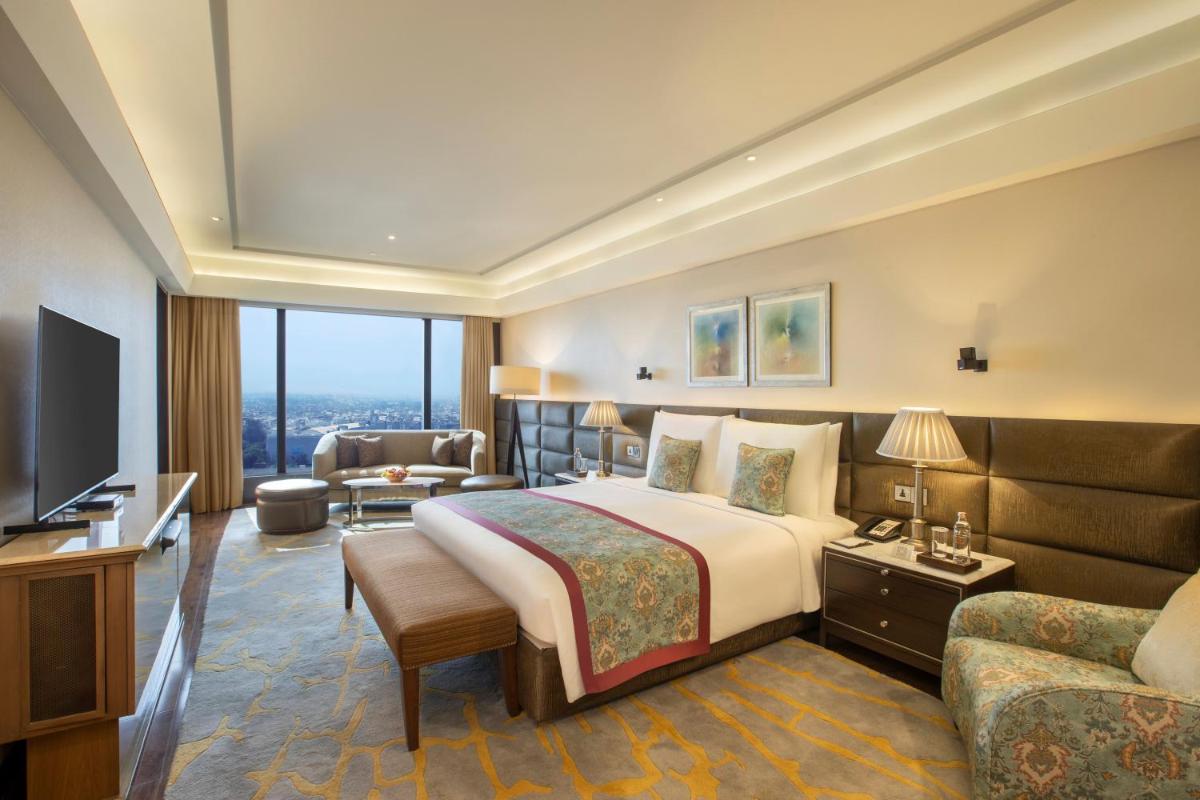 a hotel room with a bed and a television at The Leela Ambience Convention Hotel Delhi in New Delhi
