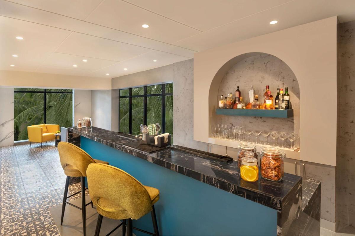 a bar with two chairs and a counter with drinks at Hyatt Place Goa Candolim in Candolim a bar with two chairs and a counter with drinks at Hyatt Place Goa Candolim in Candolim