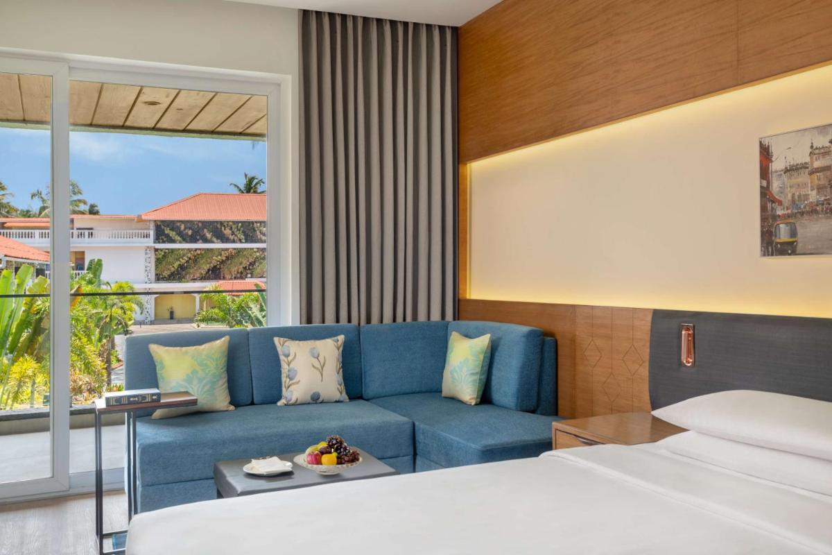 a hotel room with a bed and a couch at Hyatt Place Goa Candolim in Candolim a hotel room with a bed and a couch at Hyatt Place Goa Candolim in Candolim
