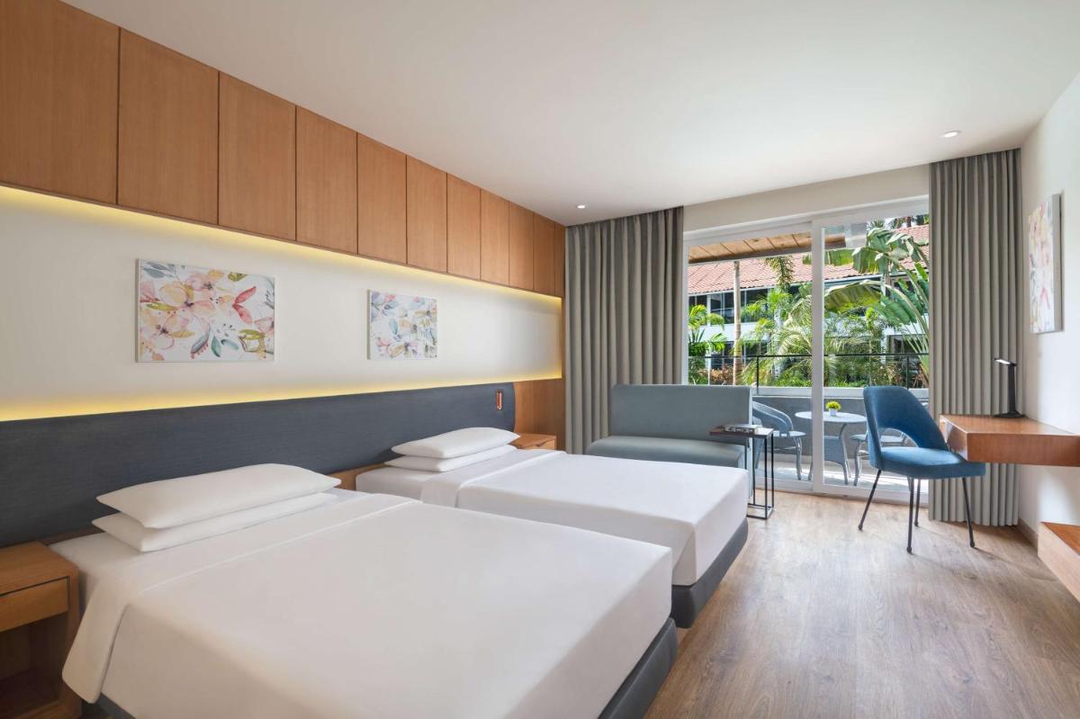a hotel room with two beds and a table at Hyatt Place Goa Candolim in Candolim a hotel room with two beds and a table at Hyatt Place Goa Candolim in Candolim